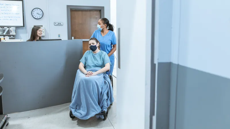 Nurse escorting a patient in a wheelchair through a hospital hallway for discharge transport
